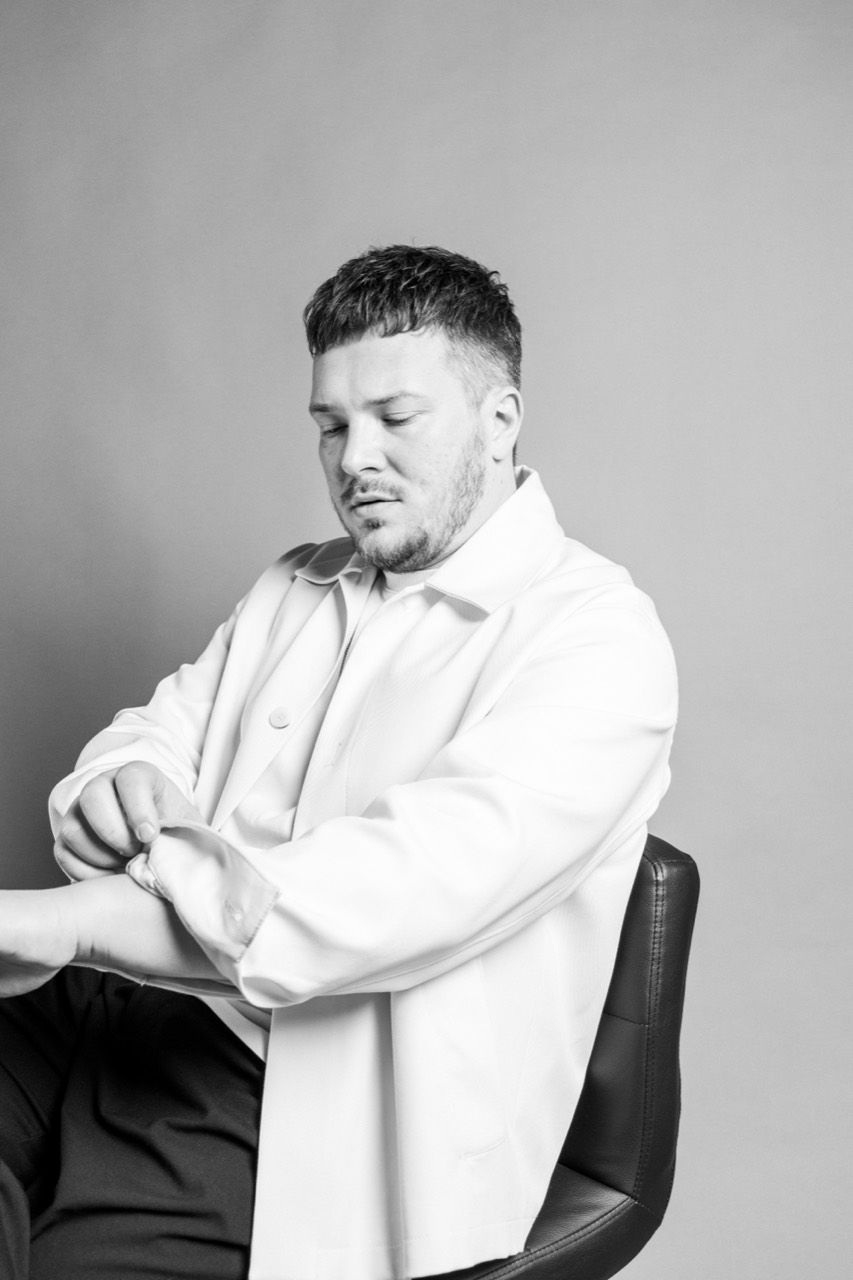 Black-and-white portrait of Anton Abrezov seated, adjusting his sleeve