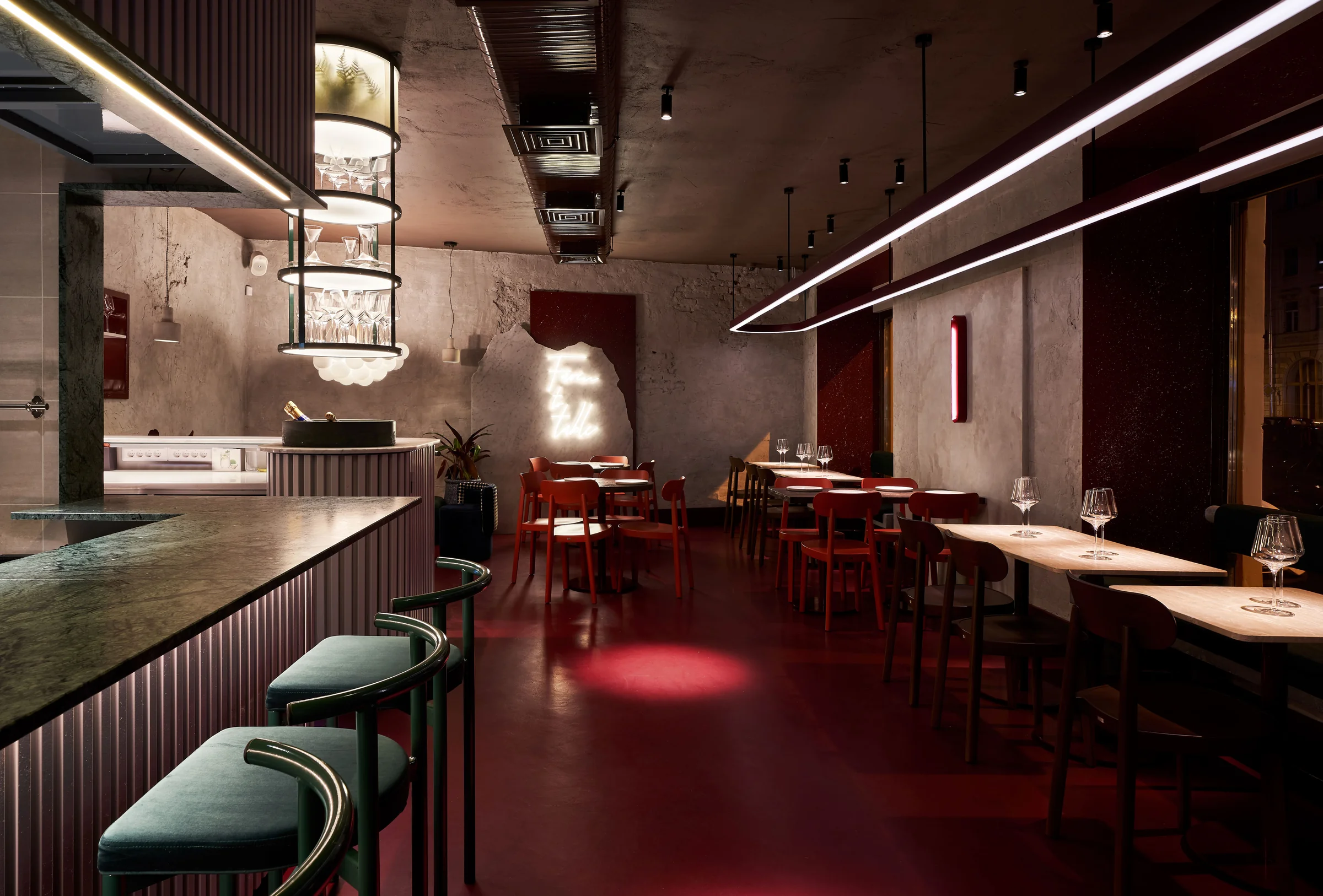Commons — dining room and open kitchen with green stools and a red floor