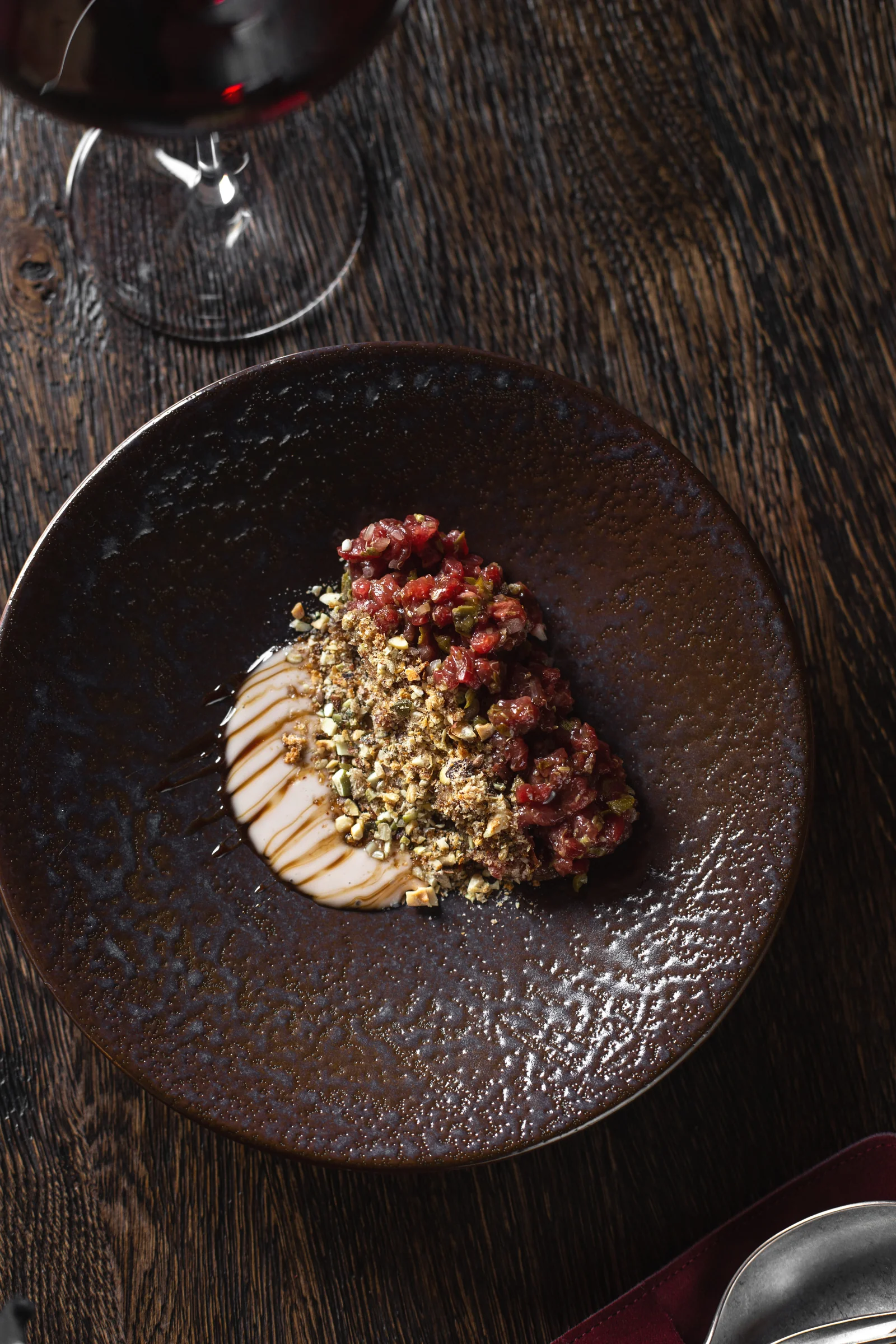 Commons — tartare on a dark plate beside a glass of wine