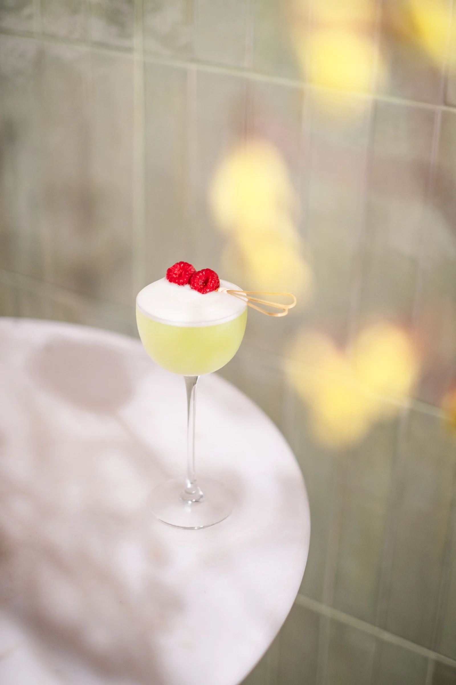 Pale green cocktail with raspberry garnish at Zula Bistro